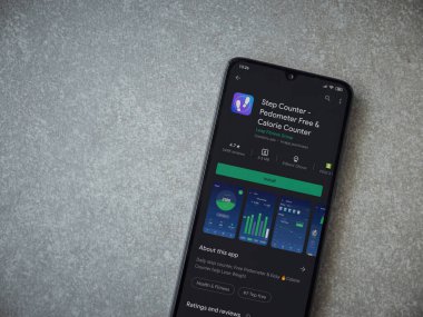 Lod, Israel - 8 Temmuz 2020: Step Counter uygulaması oyun mağazası sayfasında seramik taş zemin üzerinde siyah bir cep telefonu görüntüsü. Üst görünüm düzlüğü kopyalama alanı ile yatıyordu.