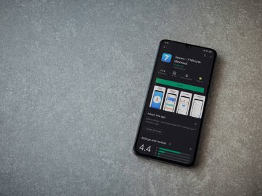 Lod, Israel - 8 Temmuz 2020: Seramik taş zemin üzerinde siyah bir cep telefonunun sergilendiği yedi uygulama oyun mağazası sayfası. Üst görünüm düzlüğü kopyalama alanı ile yatıyordu.