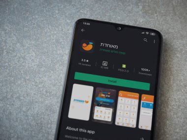 Lod, Israel - 8 Temmuz 2020: Meuhedet Sağlık Hizmetleri uygulama oyun mağazası sayfası seramik taş zemin üzerinde siyah bir cep telefonu görüntüsü. Üst görünüm düzlüğü kopyalama alanı ile yatıyordu.