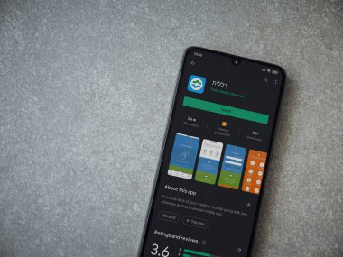 Lod, Israel - 8 Temmuz 2020: Clalit Sağlık Hizmetleri uygulama oyun mağazası sayfası seramik taş zemin üzerinde siyah bir cep telefonu görüntüsü. Üst görünüm düzlüğü kopyalama alanı ile yatıyordu.