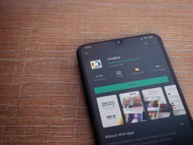 Lod, Israel - 8 Temmuz 2020: Mako app oyun mağazası sayfası ahşap arka planda siyah bir cep telefonu ekranında. Üst görünüm düzlüğü kopyalama alanı ile yatıyordu.