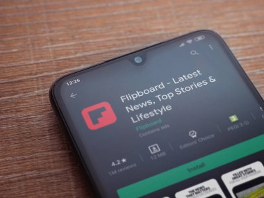 Lod, Israel - 8 Temmuz 2020: Flipboard uygulama oyun mağazası sayfası ahşap arka planda siyah bir cep telefonunun ekranında. Üst görünüm düzlüğü kopyalama alanı ile yatıyordu.