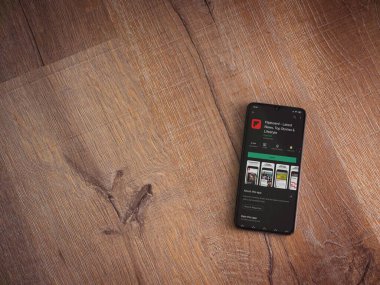 Lod, Israel - 8 Temmuz 2020: Flipboard uygulama oyun mağazası sayfası ahşap arka planda siyah bir cep telefonunun ekranında. Üst görünüm düzlüğü kopyalama alanı ile yatıyordu.