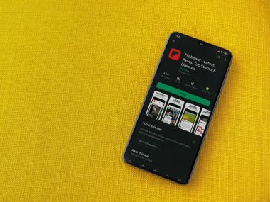 Lod, Israel - 8 Temmuz 2020: Flipboard uygulama oyun mağazası sayfası sarı kumaş arka planda siyah bir cep telefonunun ekranında. Üst görünüm düzlüğü kopyalama alanı ile yatıyordu.