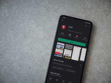 Lod, Israel - 8 Temmuz 2020: ynet uygulama oyun mağazası sayfası seramik taş zemin üzerinde siyah bir cep telefonu görüntüsü. Üst görünüm düzlüğü kopyalama alanı ile yatıyordu.