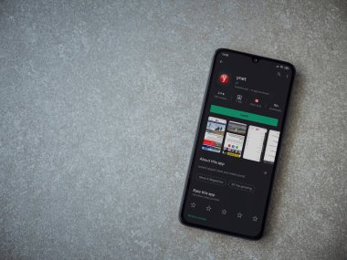 Lod, Israel - 8 Temmuz 2020: ynet uygulama oyun mağazası sayfası seramik taş zemin üzerinde siyah bir cep telefonu görüntüsü. Üst görünüm düzlüğü kopyalama alanı ile yatıyordu.