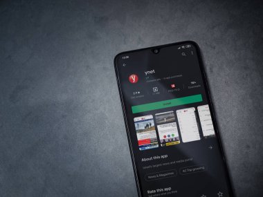 Lod, Israel - 8 Temmuz 2020: ynet uygulama oyun mağazası sayfası koyu mermer taşlı arka planda siyah bir cep telefonu ekranında. Üst görünüm düzlüğü kopyalama alanı ile yatıyordu.