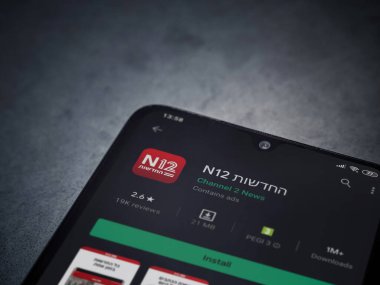 Lod, Israel - 8 Temmuz 2020: N12 uygulama oyun mağazası sayfası koyu mermer taşlı arka planda siyah bir cep telefonunun ekranında. Üst görünüm düzlüğü kopyalama alanı ile yatıyordu.