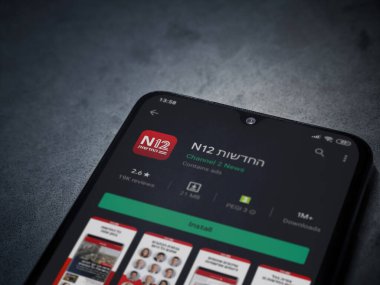 Lod, Israel - 8 Temmuz 2020: N12 uygulama oyun mağazası sayfası koyu mermer taşlı arka planda siyah bir cep telefonunun ekranında. Üst görünüm düzlüğü kopyalama alanı ile yatıyordu.