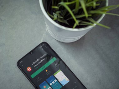 Lod, Israel - 8 Temmuz 2020: Modern minimalist ofis çalışma alanı ve Helpers uygulamalı akıllı telefon mermer arka planda oyun mağazası sayfası. Üst görünüm düzlüğü kopyalama alanı ile yatıyordu.