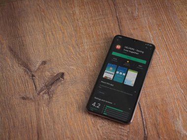 Lod, Israel - 8 Temmuz 2020: Ahşap arka planda siyah bir cep telefonunun ekranında yardımcı uygulamalar oyun mağazası sayfası. Üst görünüm düzlüğü kopyalama alanı ile yatıyordu.