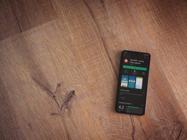 Lod, Israel - 8 Temmuz 2020: Ahşap arka planda siyah bir cep telefonunun ekranında yardımcı uygulamalar oyun mağazası sayfası. Üst görünüm düzlüğü kopyalama alanı ile yatıyordu.