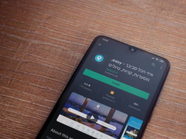 Lod, Israel - 8 Temmuz 2020: Ahşap arka planda siyah bir cep telefonu ekranında basit bir uygulama oyun mağazası sayfası. Üst görünüm düzlüğü kopyalama alanı ile yatıyordu.