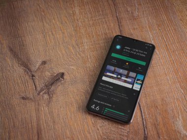 Lod, Israel - 8 Temmuz 2020: Ahşap arka planda siyah bir cep telefonu ekranında basit bir uygulama oyun mağazası sayfası. Üst görünüm düzlüğü kopyalama alanı ile yatıyordu.