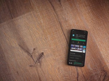 Lod, Israel - 8 Temmuz 2020: Ahşap arka planda siyah bir cep telefonu ekranında basit bir uygulama oyun mağazası sayfası. Üst görünüm düzlüğü kopyalama alanı ile yatıyordu.