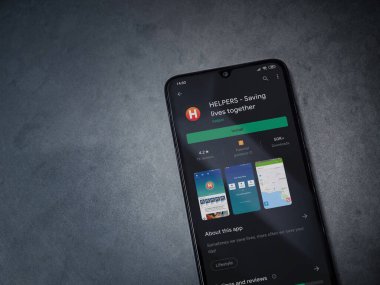 Lod, Israel - 8 Temmuz 2020: Helpers uygulama mağaza sayfası koyu mermer taşlı arka planda siyah bir cep telefonunun ekranında. Üst görünüm düzlüğü kopyalama alanı ile yatıyordu.