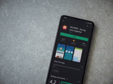 Lod, Israel - 8 Temmuz 2020: Yardımcı uygulamalar seramik taş zemin üzerinde siyah bir cep telefonu ekranında oyun mağazası sayfası. Üst görünüm düzlüğü kopyalama alanı ile yatıyordu.