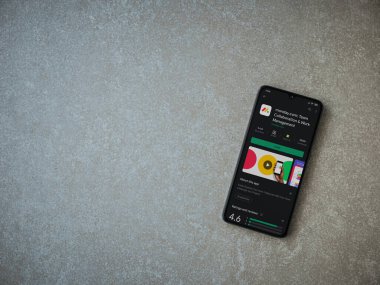 Lod, Israel - 8 Temmuz 2020: Pazartesi uygulaması oyun mağazası sayfası seramik taş zemin üzerinde siyah bir cep telefonu görüntüsü. Üst görünüm düzlüğü kopyalama alanı ile yatıyordu.