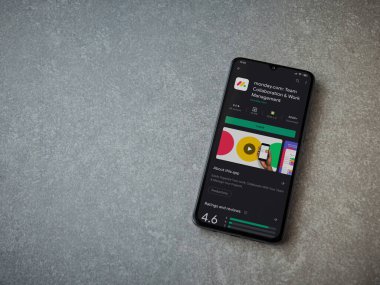 Lod, Israel - 8 Temmuz 2020: Pazartesi uygulaması oyun mağazası sayfası seramik taş zemin üzerinde siyah bir cep telefonu görüntüsü. Üst görünüm düzlüğü kopyalama alanı ile yatıyordu.