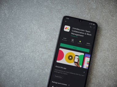 Lod, Israel - 8 Temmuz 2020: Pazartesi uygulaması oyun mağazası sayfası seramik taş zemin üzerinde siyah bir cep telefonu görüntüsü. Üst görünüm düzlüğü kopyalama alanı ile yatıyordu.