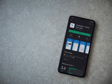Lod, Israel - 8 Temmuz 2020: Freelancer uygulama oyun mağazası sayfası seramik taş zemin üzerinde siyah bir cep telefonu görüntüsü. Üst görünüm düzlüğü kopyalama alanı ile yatıyordu.