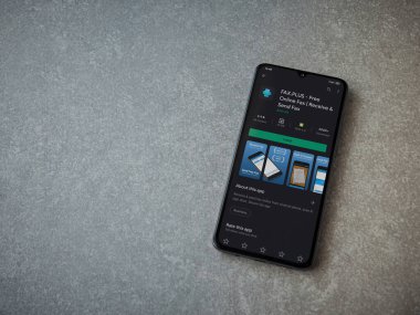 Lod, Israel - 8 Temmuz 2020: Faks Plus uygulama oyun mağazası sayfası seramik taş zemin üzerinde siyah bir cep telefonu görüntüsü. Üst görünüm düzlüğü kopyalama alanı ile yatıyordu.