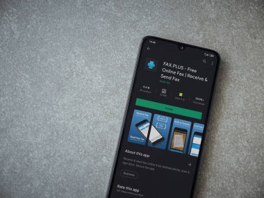 Lod, Israel - 8 Temmuz 2020: Faks Plus uygulama oyun mağazası sayfası seramik taş zemin üzerinde siyah bir cep telefonu görüntüsü. Üst görünüm düzlüğü kopyalama alanı ile yatıyordu.