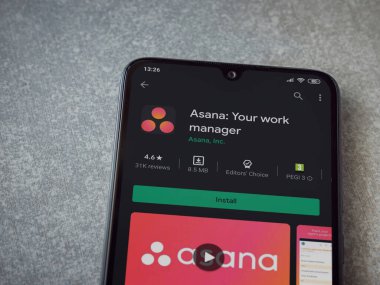 Lod, Israel - 8 Temmuz 2020: Asana uygulaması oyun mağazası sayfası seramik taş zemin üzerinde siyah bir cep telefonu görüntüsü. Üst görünüm düzlüğü kopyalama alanı ile yatıyordu.