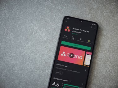 Lod, Israel - 8 Temmuz 2020: Asana uygulaması oyun mağazası sayfası seramik taş zemin üzerinde siyah bir cep telefonu görüntüsü. Üst görünüm düzlüğü kopyalama alanı ile yatıyordu.