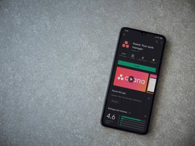 Lod, Israel - 8 Temmuz 2020: Asana uygulaması oyun mağazası sayfası seramik taş zemin üzerinde siyah bir cep telefonu görüntüsü. Üst görünüm düzlüğü kopyalama alanı ile yatıyordu.