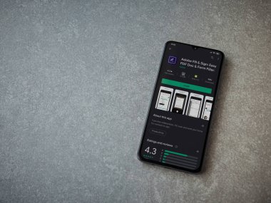 Lod, Israel - 8 Temmuz 2020: Seramik taş zemin üzerinde siyah bir cep telefonunun gösterildiği Adobe Doldur ve İmzala uygulaması oyun mağazası sayfası. Üst görünüm düzlüğü kopyalama alanı ile yatıyordu.