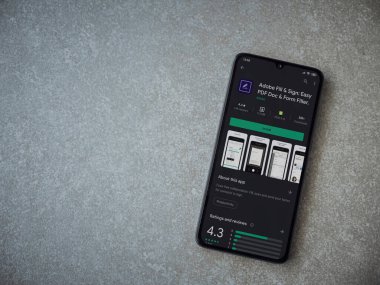 Lod, Israel - 8 Temmuz 2020: Seramik taş zemin üzerinde siyah bir cep telefonunun gösterildiği Adobe Doldur ve İmzala uygulaması oyun mağazası sayfası. Üst görünüm düzlüğü kopyalama alanı ile yatıyordu.