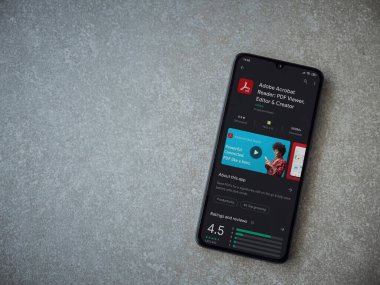 Lod, Israel - 8 Temmuz 2020: Adobe Acrobat Reader uygulama oyun mağazası sayfası seramik taş zemin üzerinde siyah bir cep telefonu görüntüsü. Üst görünüm düzlüğü kopyalama alanı ile yatıyordu.