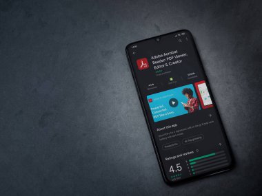 Lod, Israel - 8 Temmuz 2020: Adobe Acrobat Reader uygulama oyun mağazası sayfası koyu mermer taştan arka planda siyah bir cep telefonu görüntüsü. Üst görünüm düzlüğü kopyalama alanı ile yatıyordu.