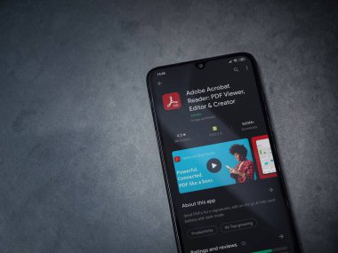 Lod, Israel - 8 Temmuz 2020: Adobe Acrobat Reader uygulama oyun mağazası sayfası koyu mermer taştan arka planda siyah bir cep telefonu görüntüsü. Üst görünüm düzlüğü kopyalama alanı ile yatıyordu.