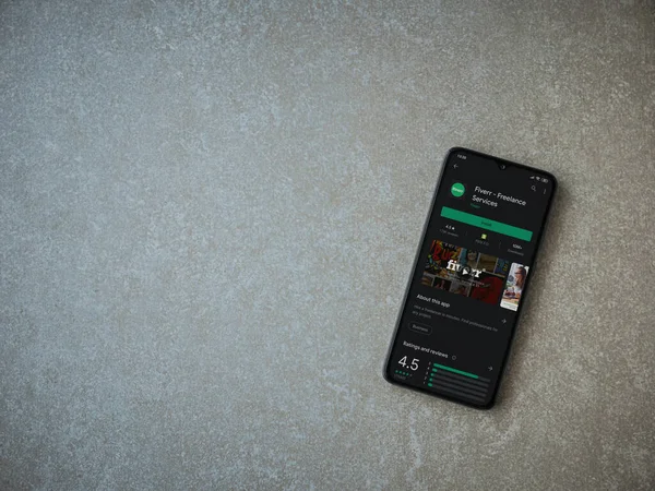 Lod, Israel - 8 Temmuz 2020: Fiverr uygulaması oyun mağazası sayfası seramik taş zemin üzerinde siyah bir cep telefonu görüntüsü. Üst görünüm düzlüğü kopyalama alanı ile yatıyordu.