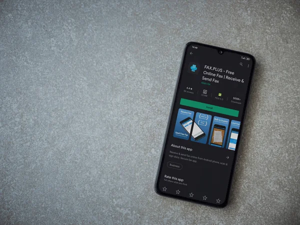 Lod, Israel - 8 Temmuz 2020: Faks Plus uygulama oyun mağazası sayfası seramik taş zemin üzerinde siyah bir cep telefonu görüntüsü. Üst görünüm düzlüğü kopyalama alanı ile yatıyordu.