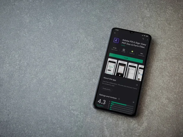 Lod, Israel - 8 Temmuz 2020: Seramik taş zemin üzerinde siyah bir cep telefonunun gösterildiği Adobe Doldur ve İmzala uygulaması oyun mağazası sayfası. Üst görünüm düzlüğü kopyalama alanı ile yatıyordu.