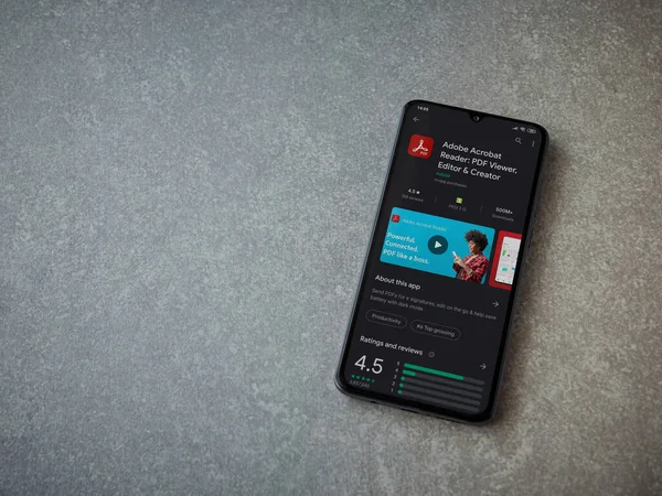 Lod, Israel - 8 Temmuz 2020: Adobe Acrobat Reader uygulama oyun mağazası sayfası seramik taş zemin üzerinde siyah bir cep telefonu görüntüsü. Üst görünüm düzlüğü kopyalama alanı ile yatıyordu.