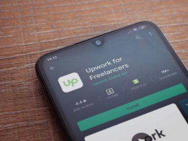 Lod, Israel - 8 Temmuz 2020: Freelancers uygulama oyun mağazası sayfası için ahşap arka planda siyah bir cep telefonu görüntüsü. Üst görünüm düzlüğü kopyalama alanı ile yatıyordu.