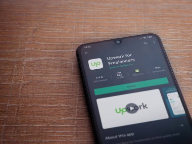 Lod, Israel - 8 Temmuz 2020: Freelancers uygulama oyun mağazası sayfası için ahşap arka planda siyah bir cep telefonu görüntüsü. Üst görünüm düzlüğü kopyalama alanı ile yatıyordu.