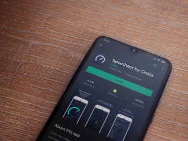 Lod, Israel - 8 Temmuz 2020: Ahşap arka planda siyah bir cep telefonunun ekranında en hızlı uygulama oyun mağazası sayfası. Üst görünüm düzlüğü kopyalama alanı ile yatıyordu.