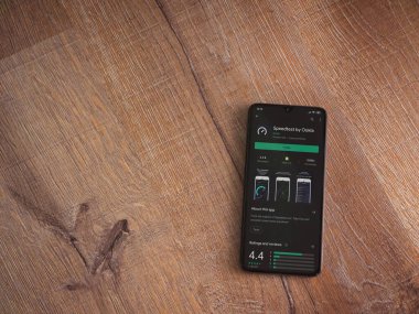 Lod, Israel - 8 Temmuz 2020: Ahşap arka planda siyah bir cep telefonunun ekranında en hızlı uygulama oyun mağazası sayfası. Üst görünüm düzlüğü kopyalama alanı ile yatıyordu.