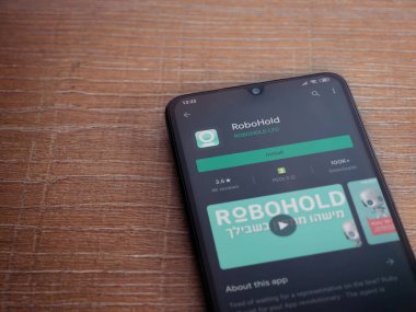 Lod, Israel - 8 Temmuz 2020: RoboHold uygulama oyun mağazası sayfası ahşap arka planda siyah bir cep telefonu ekranında. Üst görünüm düzlüğü kopyalama alanı ile yatıyordu.