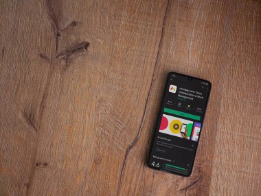 Lod, Israel - 8 Temmuz 2020: Pazartesi uygulama oyun mağazası sayfası ahşap arka planda siyah bir cep telefonunun ekranında. Üst görünüm düzlüğü kopyalama alanı ile yatıyordu.