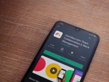 Lod, Israel - 8 Temmuz 2020: Pazartesi uygulama oyun mağazası sayfası ahşap arka planda siyah bir cep telefonunun ekranında. Üst görünüm düzlüğü kopyalama alanı ile yatıyordu.