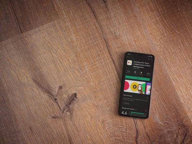 Lod, Israel - 8 Temmuz 2020: Pazartesi uygulama oyun mağazası sayfası ahşap arka planda siyah bir cep telefonunun ekranında. Üst görünüm düzlüğü kopyalama alanı ile yatıyordu.