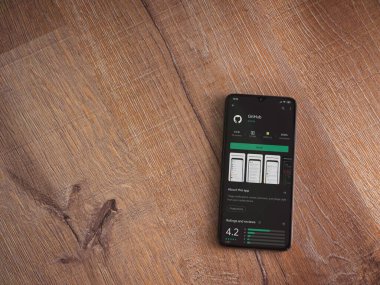 Lod, Israel - 8 Temmuz 2020: GitHub uygulama oyun mağazası sayfası ahşap arka planda siyah bir cep telefonunun ekranında. Üst görünüm düzlüğü kopyalama alanı ile yatıyordu.