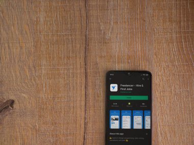 Lod, Israel - 8 Temmuz 2020: Freelancer uygulama oyun mağazası sayfası ahşap arka planda siyah bir cep telefonunun ekranında. Üst görünüm düzlüğü kopyalama alanı ile yatıyordu.