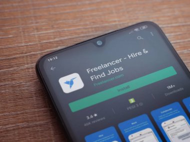 Lod, Israel - 8 Temmuz 2020: Freelancer uygulama oyun mağazası sayfası ahşap arka planda siyah bir cep telefonunun ekranında. Üst görünüm düzlüğü kopyalama alanı ile yatıyordu.
